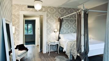 Une chambre à coucher avec un lit à baldaquin, une table de chevet, une chaise et une porte donnant sur une autre pièce.
