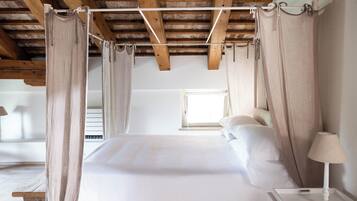 A four-poster canopy bed with a wooden ceiling and a window in the background.