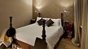 A neatly made bed with a wooden headboard, two bedside tables with lamps, and a curtain on the window.