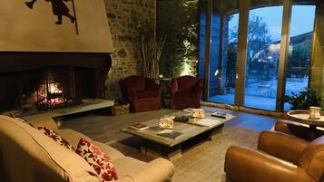 A cozy living room with a fireplace, leather sofas, and a large window overlooking a garden.
