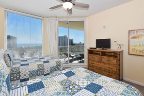 A bedroom with a large window, a ceiling fan, a wooden dresser, and a framed picture on the wall. - Open-concept, fully equipped condo w/private balcony! 🌴 (Destin)