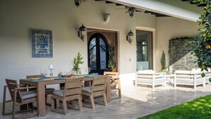 Un área de comedor al aire libre con una mesa dispuesta para cuatro personas, rodeada de sillas de madera.