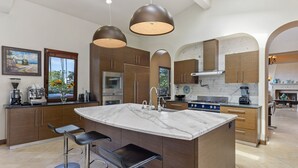 Una cocina moderna con una isla grande, electrodomésticos de acero inoxidable y armarios de madera.