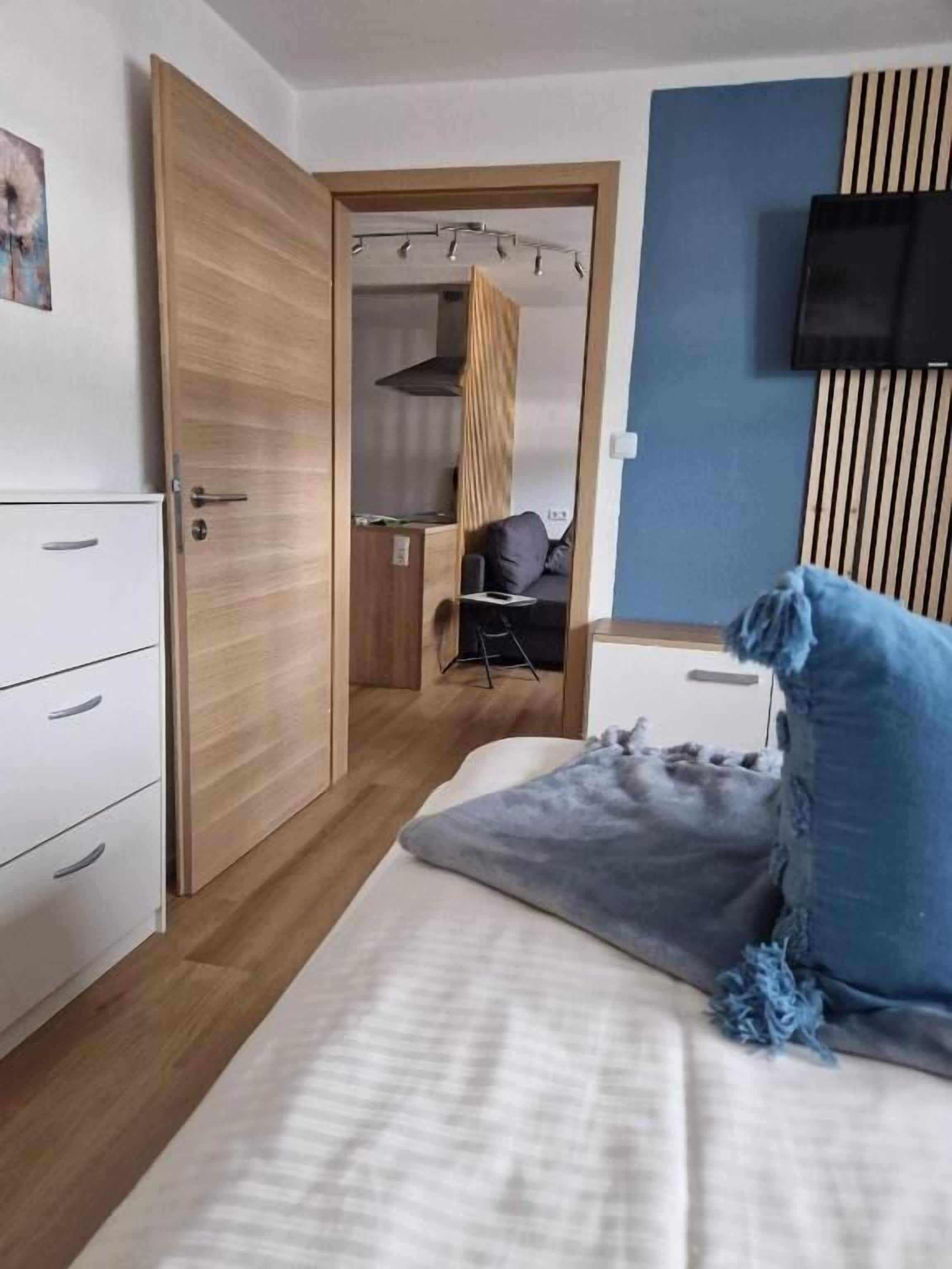 Une chambre à coucher de taille modeste, comprenant un lit, une armoire, un bureau et un téléviseur.