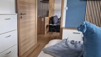 Une chambre à coucher de taille modeste, comprenant un lit, une armoire, un bureau et un téléviseur.