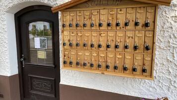 A wooden locker wall with multiple locks, a brown door, and a sign above it.