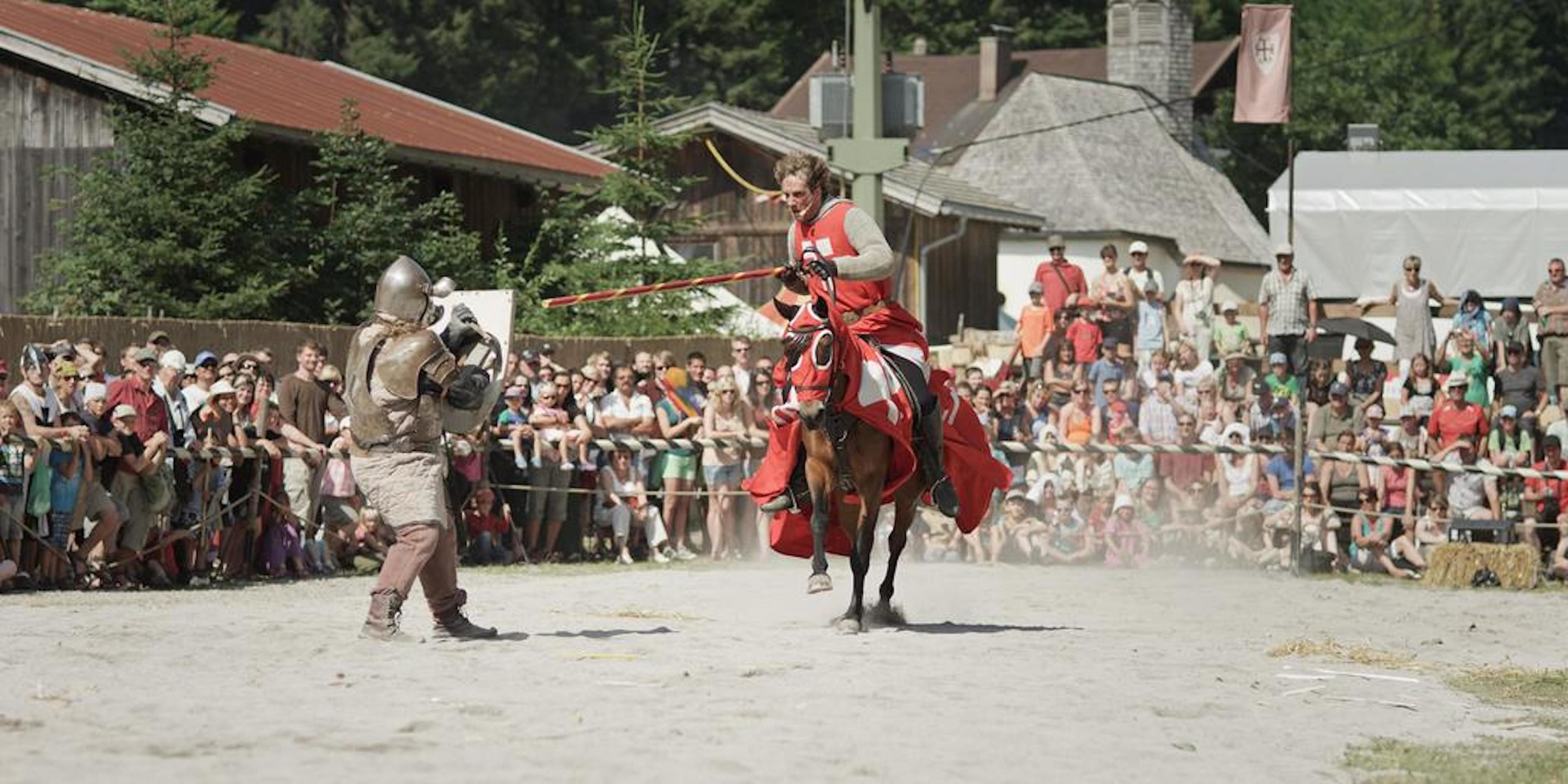A medieval jousting scene with a knight on horseback and a man on foot.