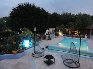 A pool area with two wire mesh chairs, a small table, and a decorative fountain. - Chez Papy et Mamy (Saint-Chef)