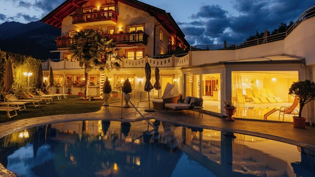 A hotel with a pool, outdoor seating, and a mountain backdrop. - Adults Only Hotel Grafenstein (Schenna)