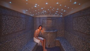 A person sitting in a tiled sauna room with a central hot tub. - Adults Only Hotel Grafenstein (Schenna)
