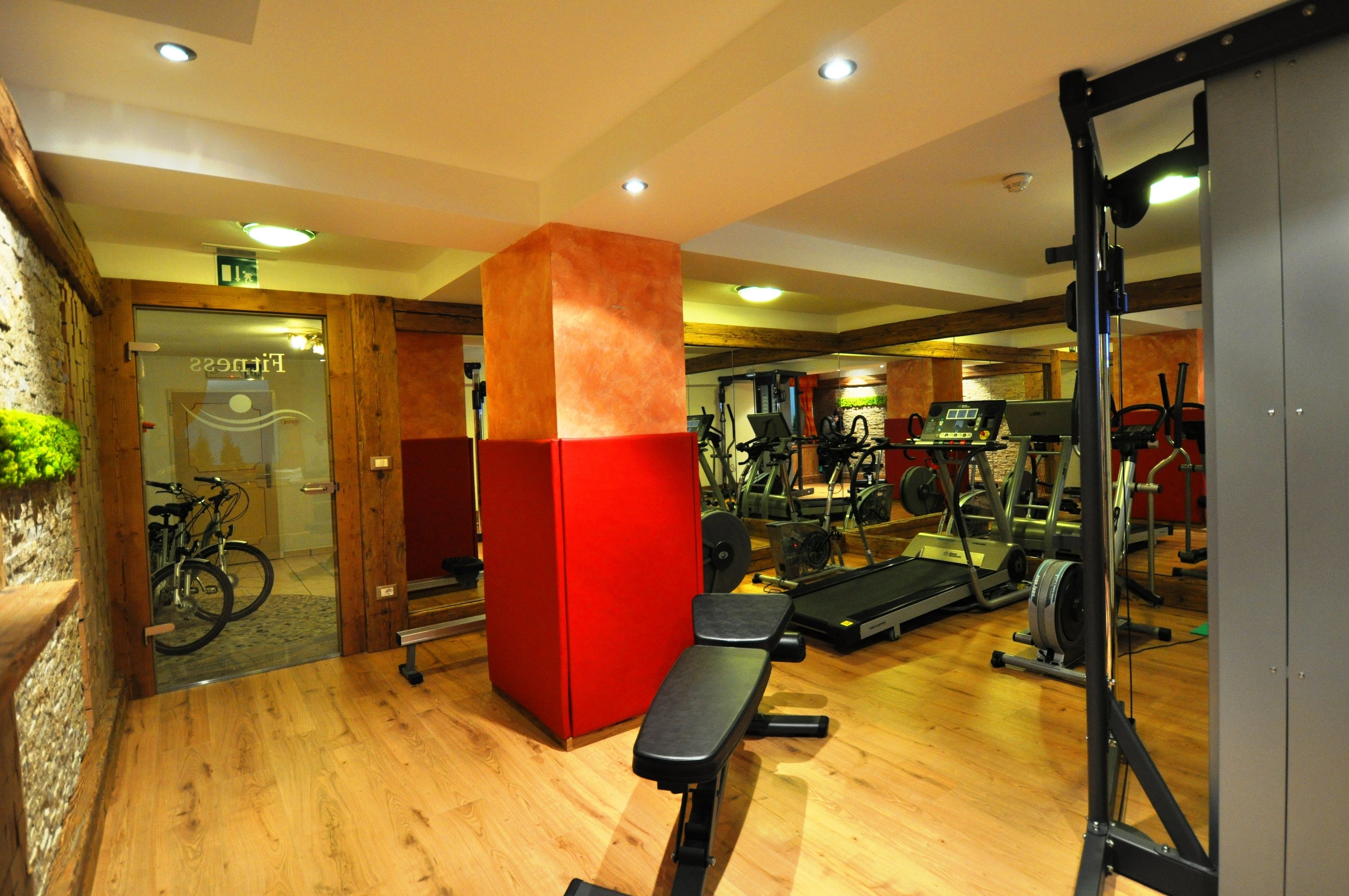 Una palestra con pavimento in legno, attrezzature per esercizi e un pilastro rosso.