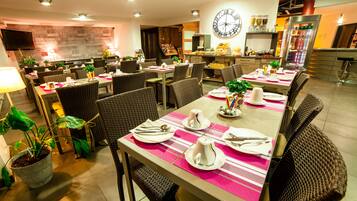 A restaurant with multiple dining tables, each set with plates, cutlery, and napkins.