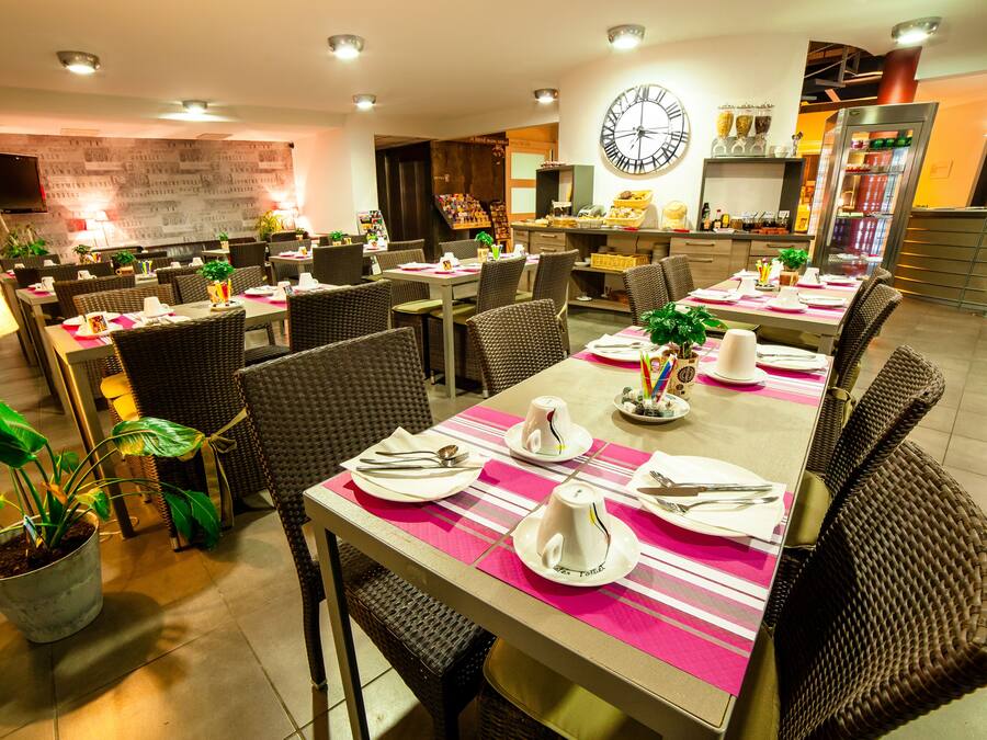 A restaurant with multiple dining tables, each set with plates, cutlery, and napkins.