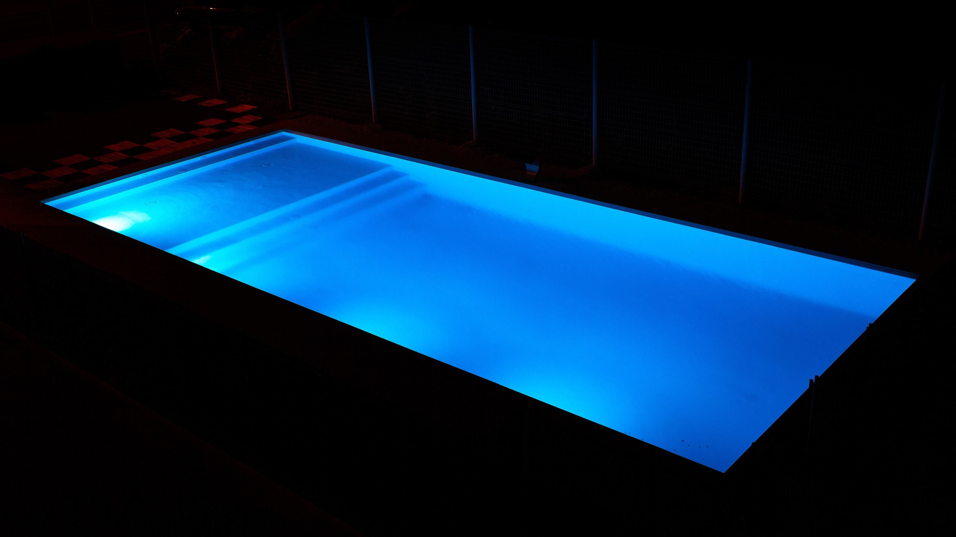 Een rechthoekig zwembad met blauw licht.