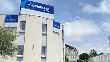 Un edificio de hotel con varios letreros que indican “The Originals City Hotel” y “Hotel Domes”.