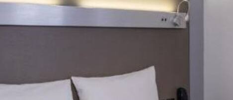 Ein Hotelzimmer mit Bett, roter Tagesdecke und einem modernen Kopfteil mit integrierter Beleuchtung.
