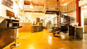 Un moderno vestíbulo de hotel con mostrador de recepción, una escalera y un área de descanso.