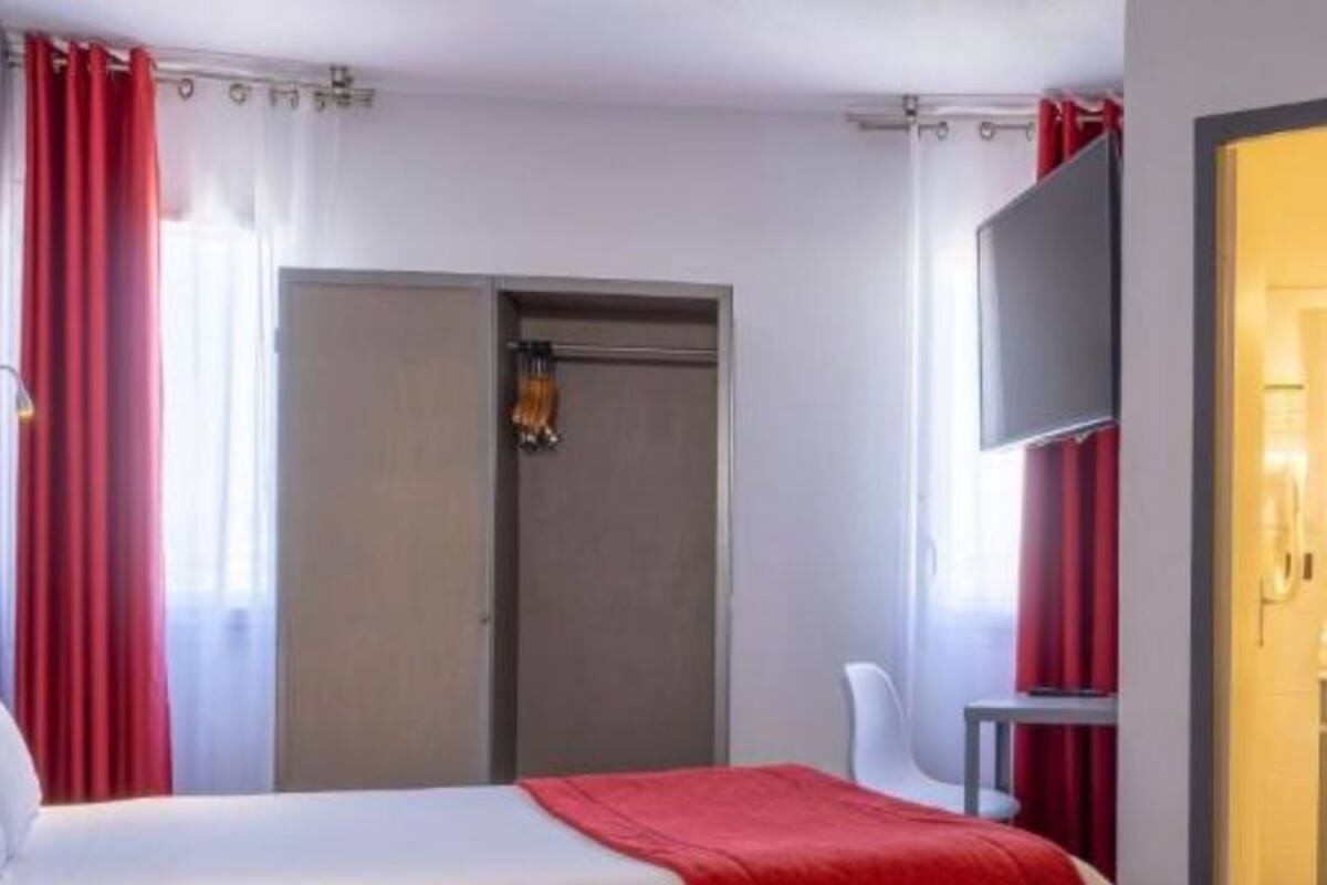 A hotel room with a bed, a wardrobe, a mirror, and a bathroom visible through an open door.