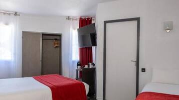Camera d'albergo con due letti, una televisione, una porta e un piccolo tavolo con una sedia.