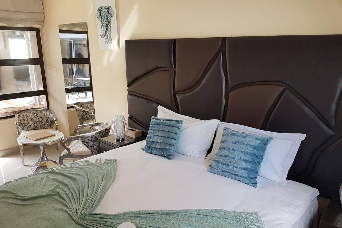 Ein Hotelzimmer mit einem großen Bett, einem Kopfteil, einem Nachttisch, einem Sessel und einem Fenster.