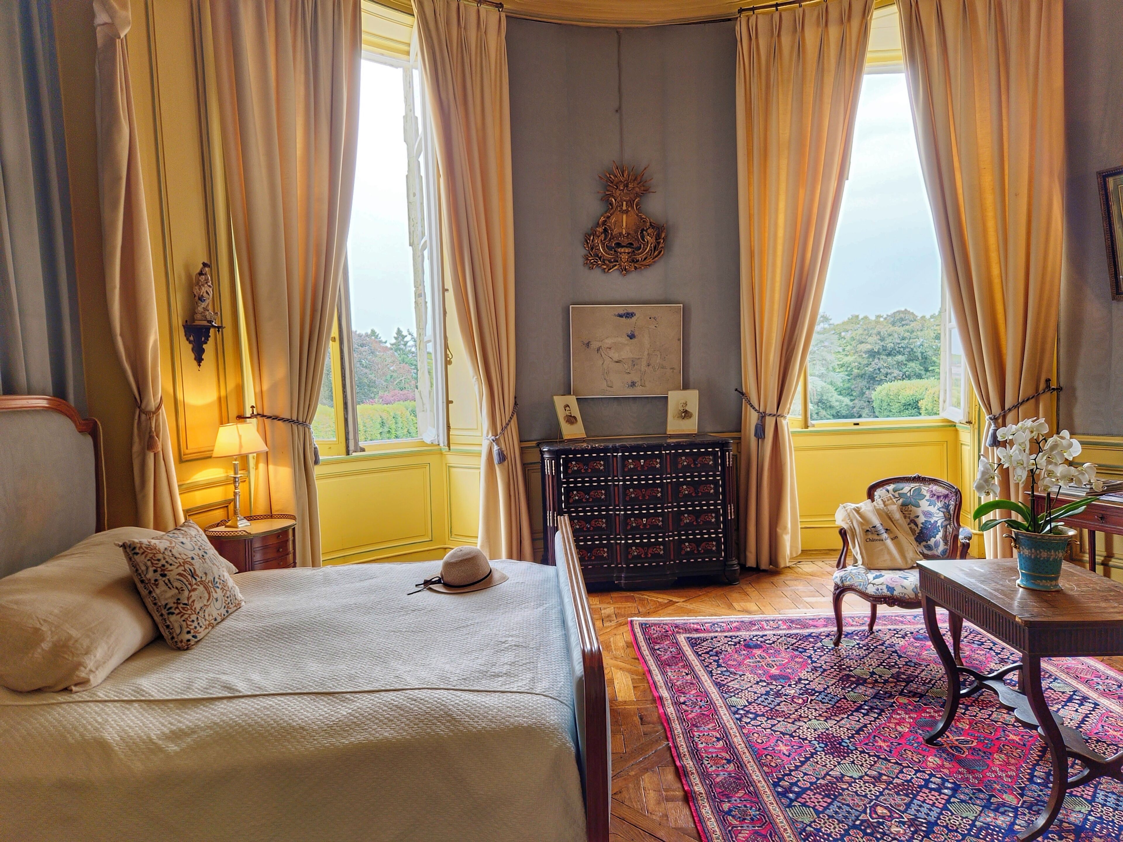 A bedroom with a bed, a desk, a chair, a dresser, and a view of the outdoors.