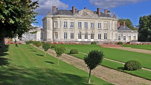 A large, historic building with symmetrical architecture, a well-maintained lawn, and formal garden design. - Chateau de Craon (Craon)