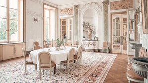 A spacious dining room with a large round table, multiple chairs, and a decorative rug. - Chateau de Craon (Craon)