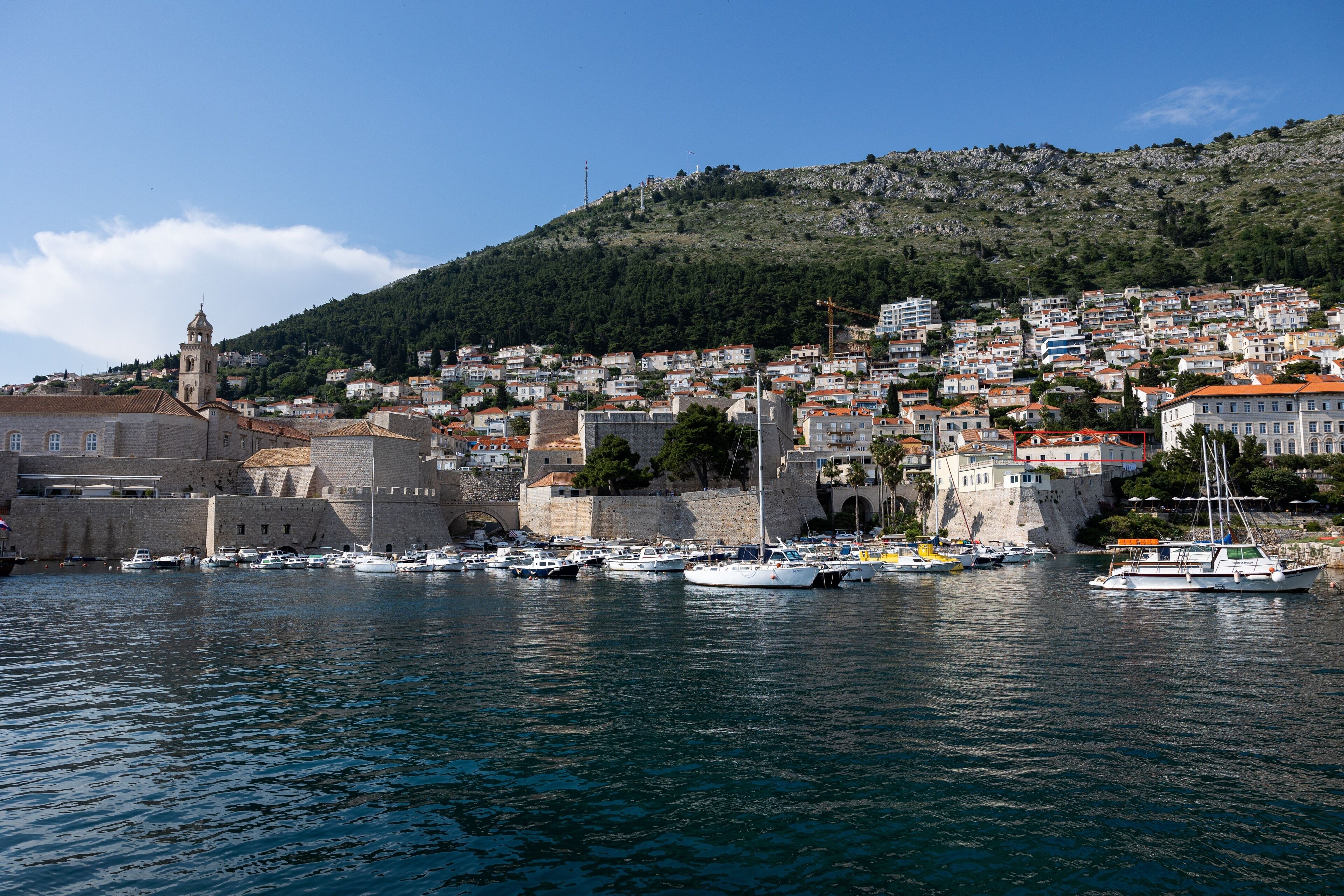 A coastal town with historic buildings, a prominent tower, and a harbor with boats.