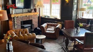 Een gezellige woonkamer met een open haard, comfortabele zithoek, een eettafel en een televisie.