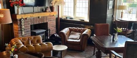 Una sala de estar acogedora con chimenea, asientos cómodos, una mesa de comedor y un televisor.