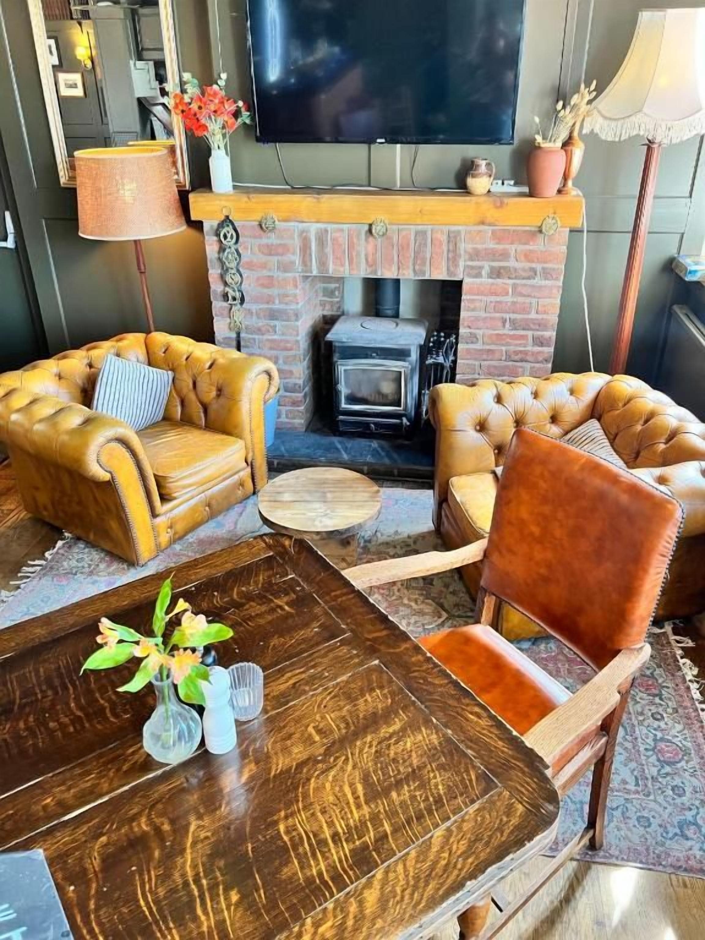 Una sala acogedora con sillones de cuero, una mesa de centro de madera y una chimenea.