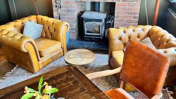 Una sala acogedora con sillones de cuero, una mesa de centro de madera y una chimenea.