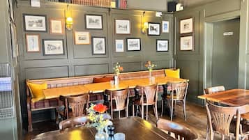 A dining area with a long wooden table, multiple chairs, a bench, and framed pictures on the wall.