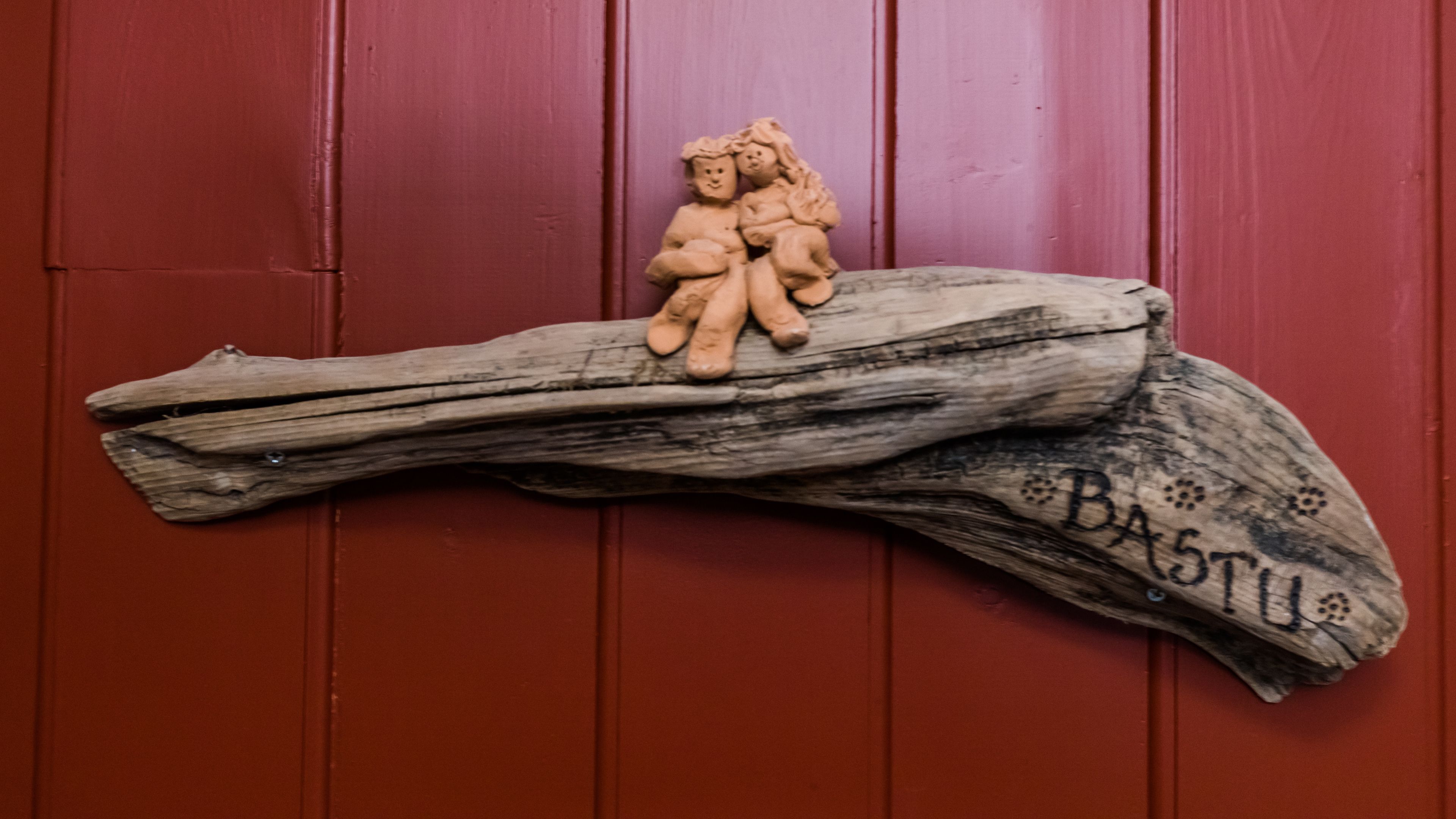 A rustic wooden sign with the word "Bastille" carved into it, mounted on a wall.