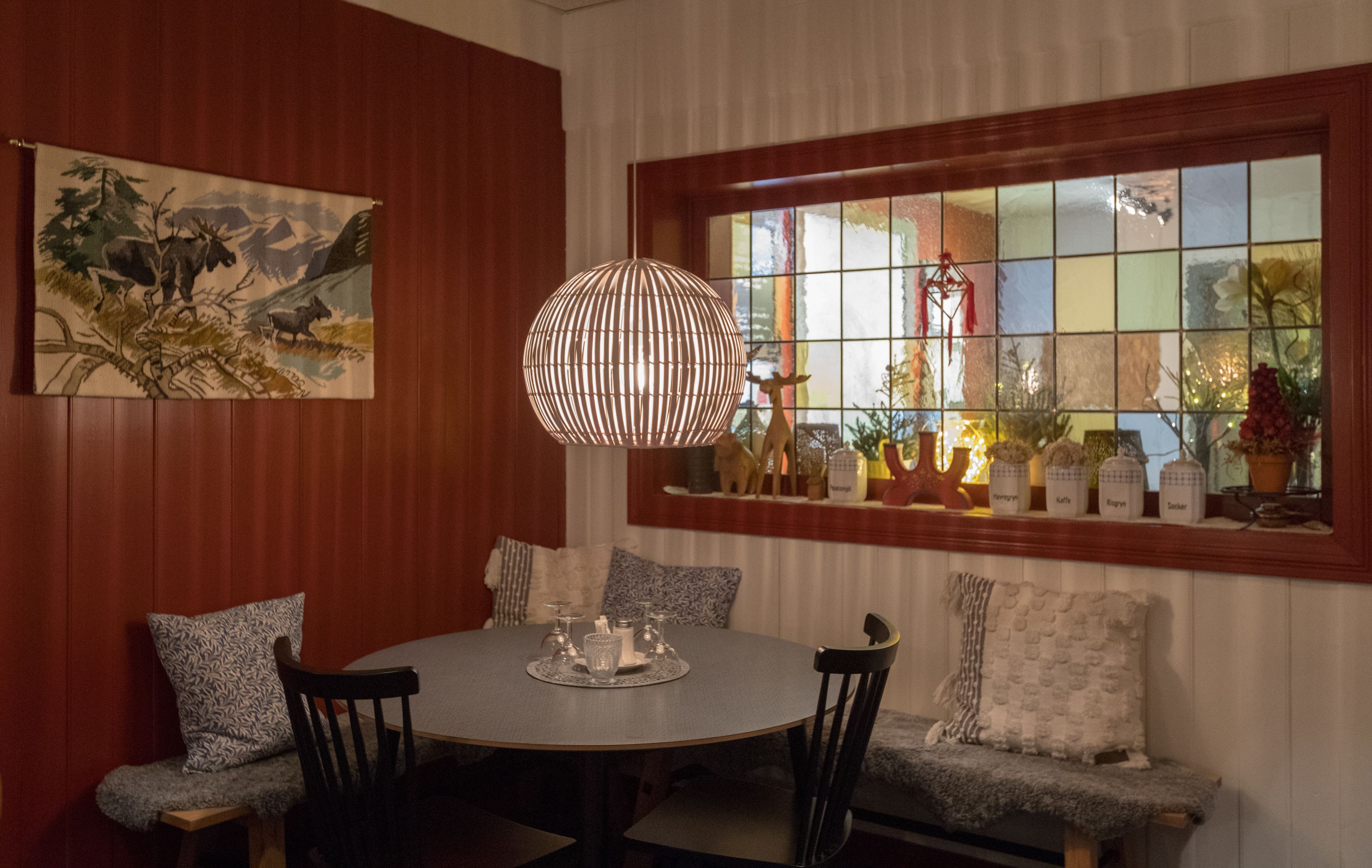 A dining area with a round table, chairs, and a hanging light fixture.