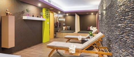A spa area with wooden loungers, a stone wall, and a reception desk with a statue.