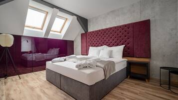Un dormitorio moderno con una cama grande, un cabecero tapizado en rojo y un tragaluz.