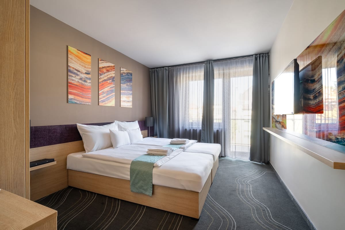 A hotel room with a large bed, a desk, and a window with curtains.