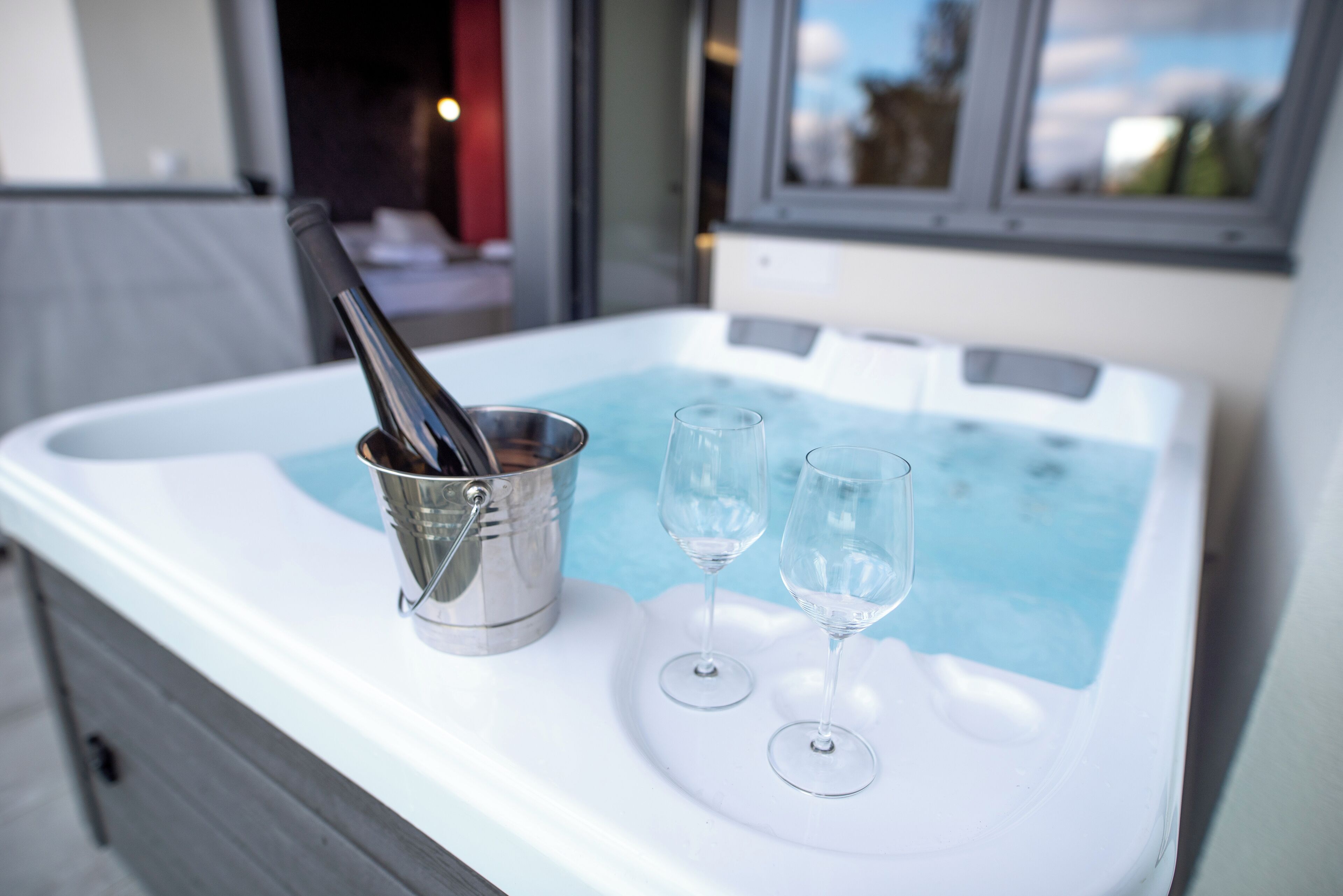 Un bain à remous avec deux verres à vin et une bouteille de champagne dans un seau en métal.