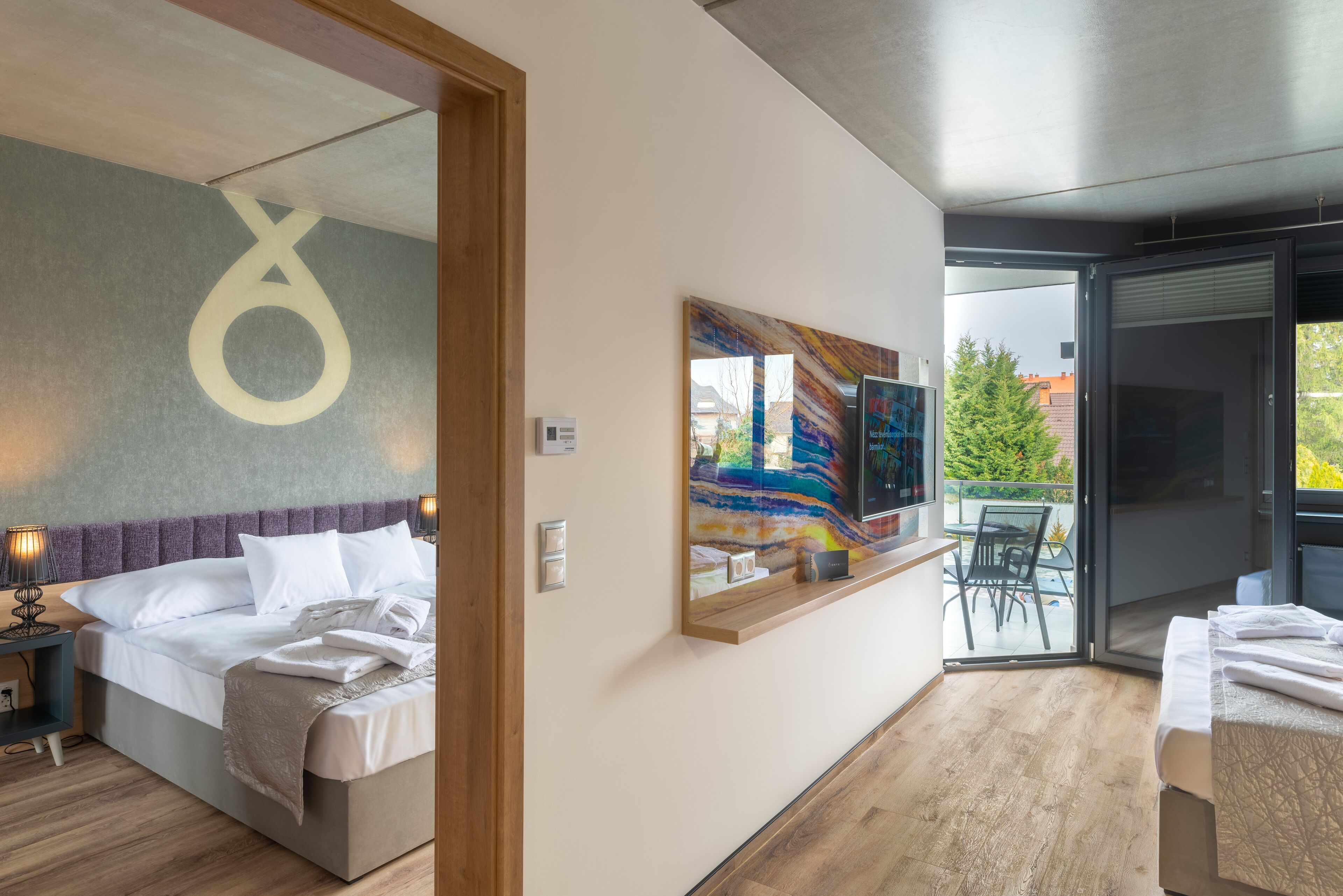 Ein modernes Hotelzimmer mit einem Bett, einem großen Spiegel, einem Gemälde und Blick ins Freie.