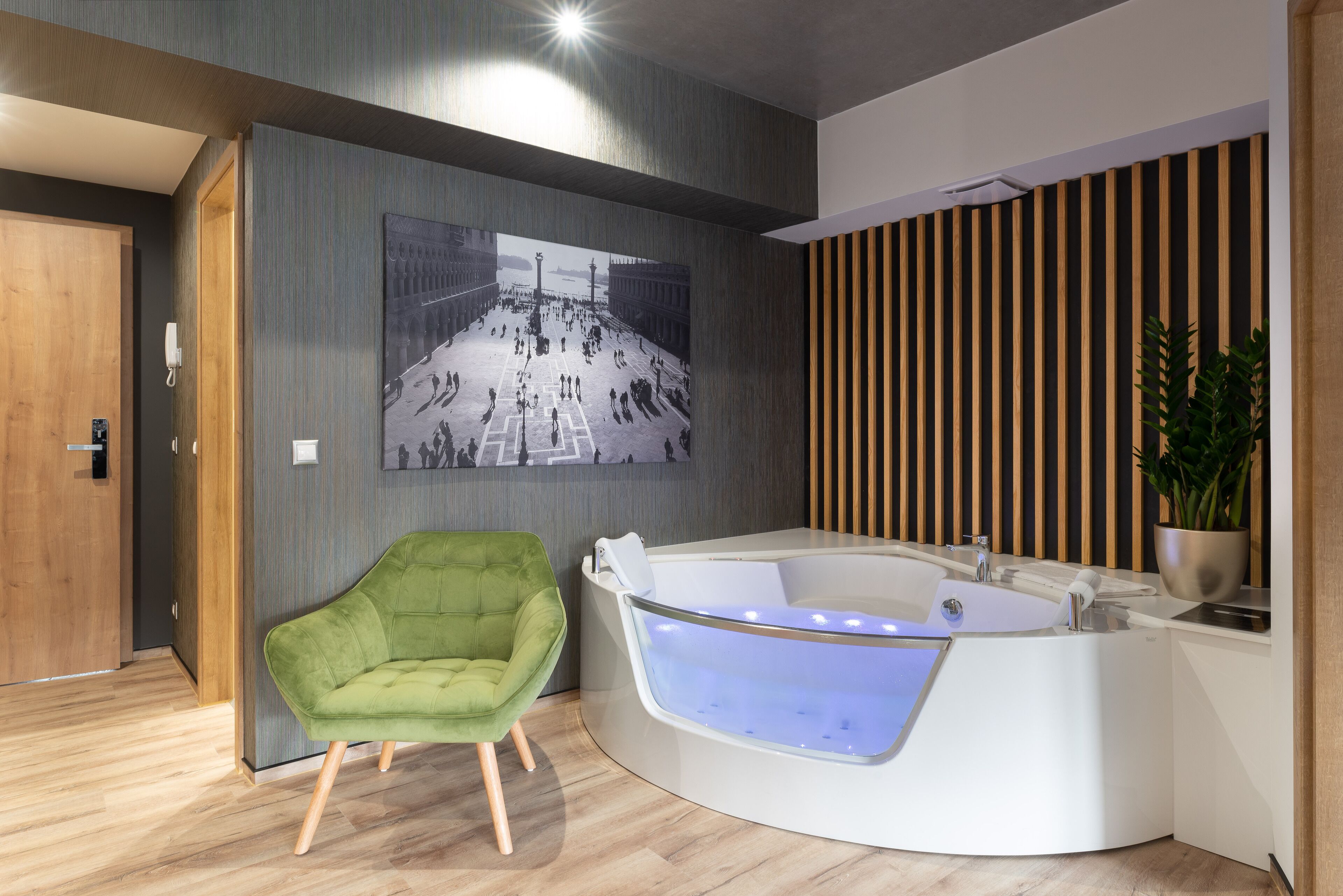 Un baño moderno con una silla verde, una bañera grande y un revestimiento de listones de madera.