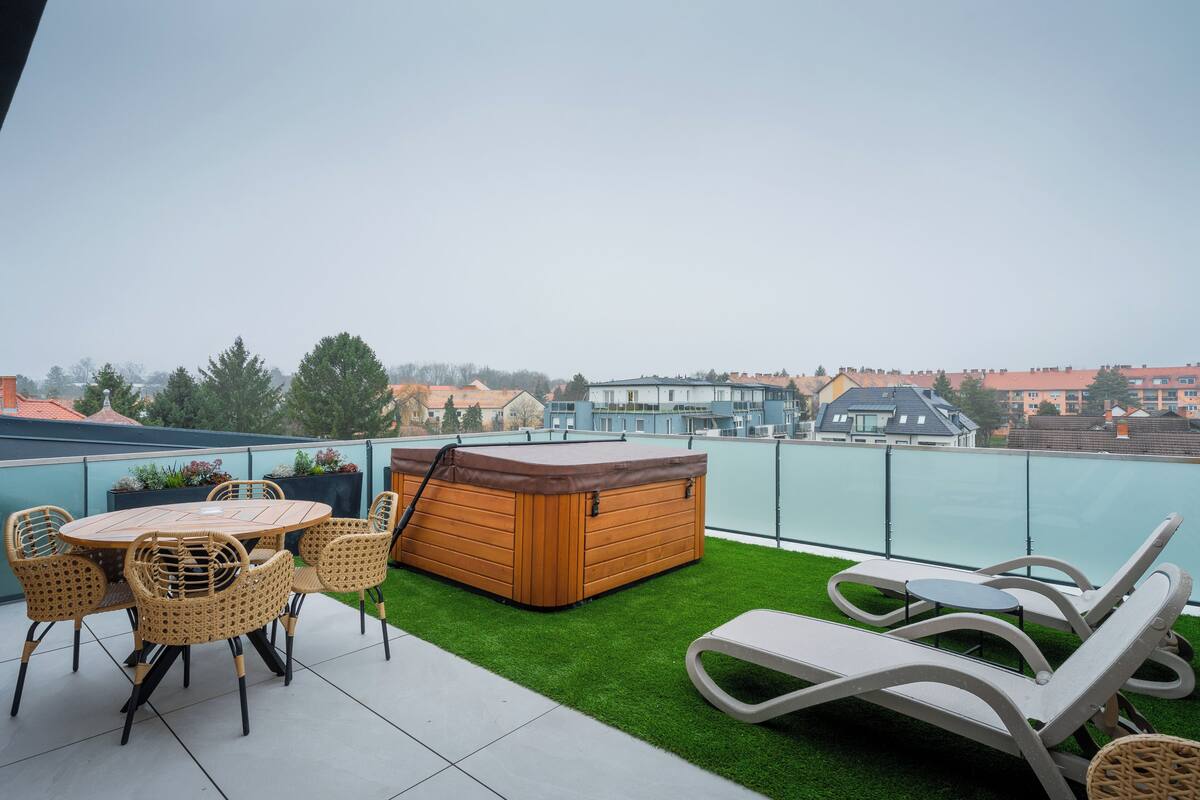 A rooftop terrace with a hot tub, lounge chairs, and a dining set.