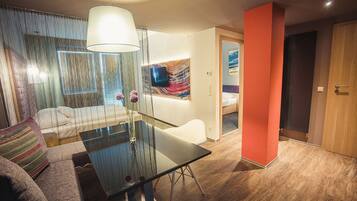 Una habitación de hotel moderna con una mesa de comedor de vidrio, un sofá y una cama.