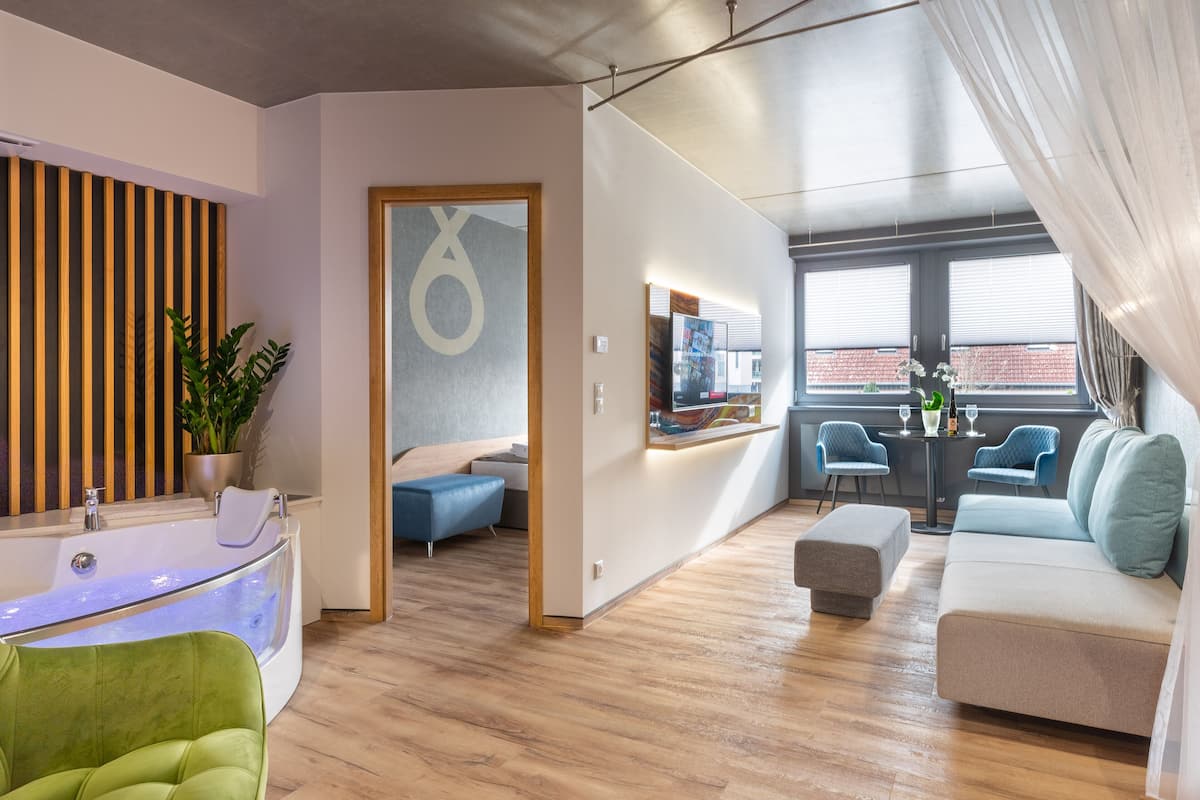 A modern living room with a bathtub, a sofa, and a dining area with chairs.
