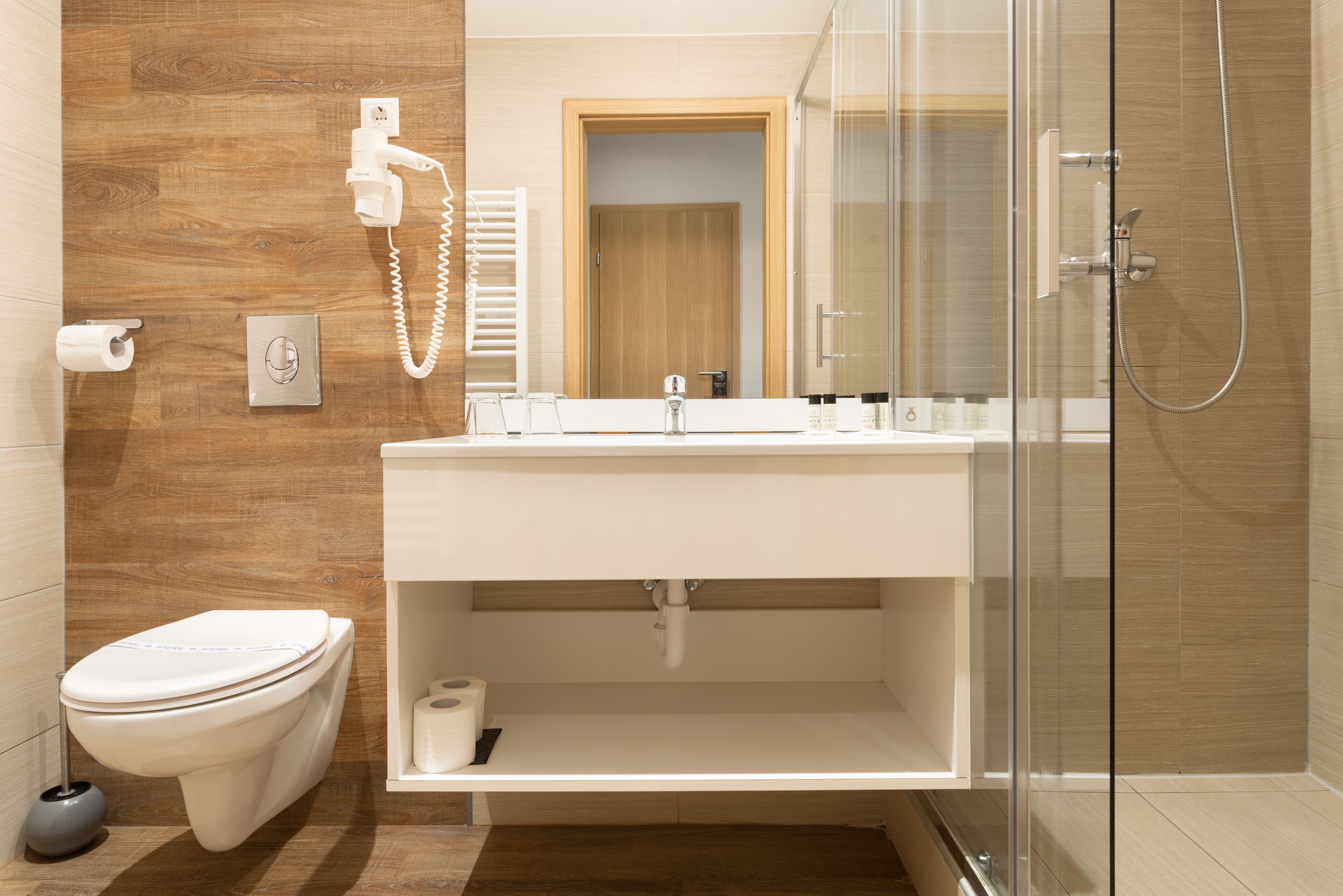 Un baño moderno con inodoro, lavamanos y ducha.