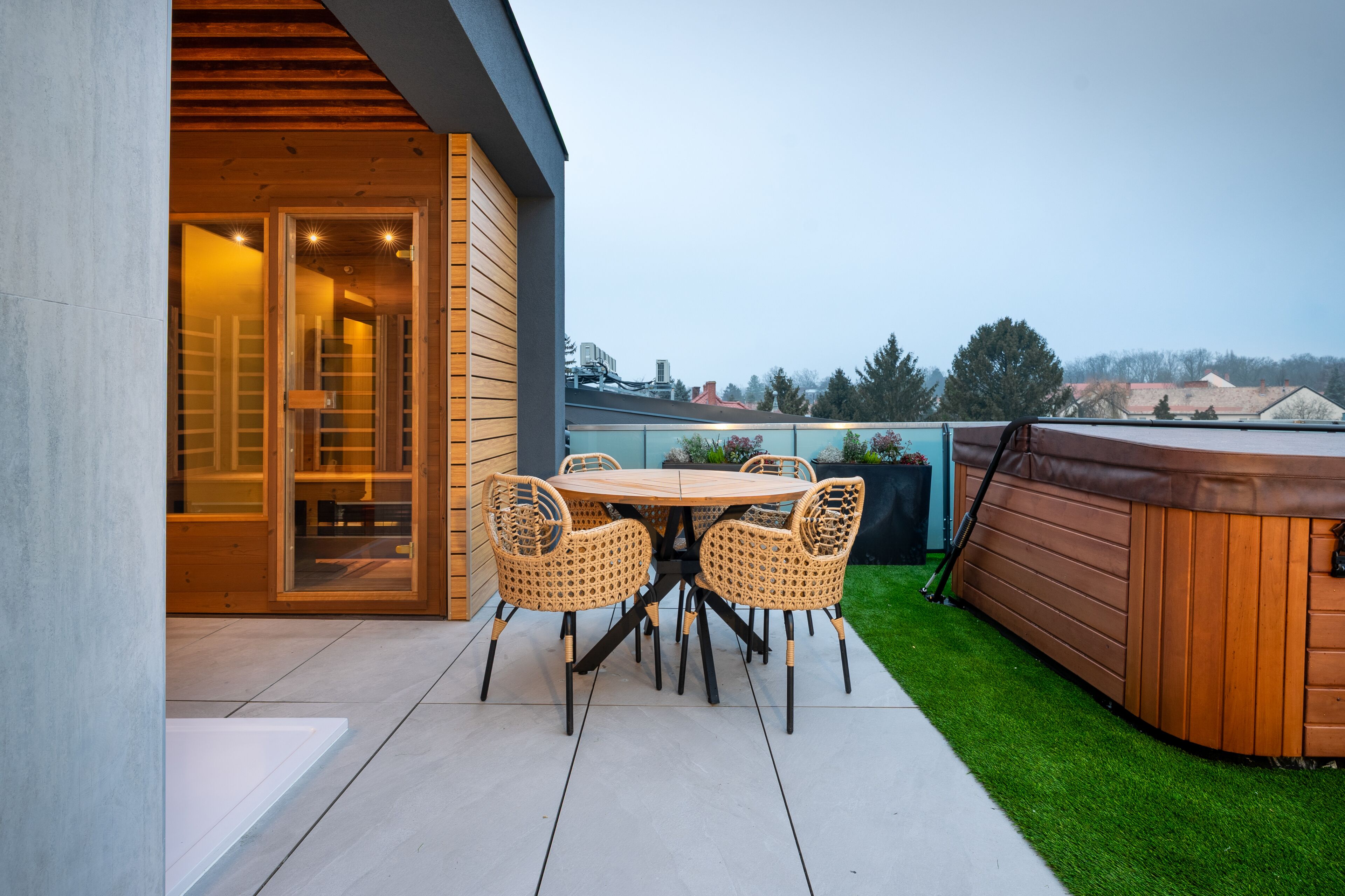 Eine Terrasse mit rundem Tisch und Stühlen, einem Whirlpool und einem Holzboden.
