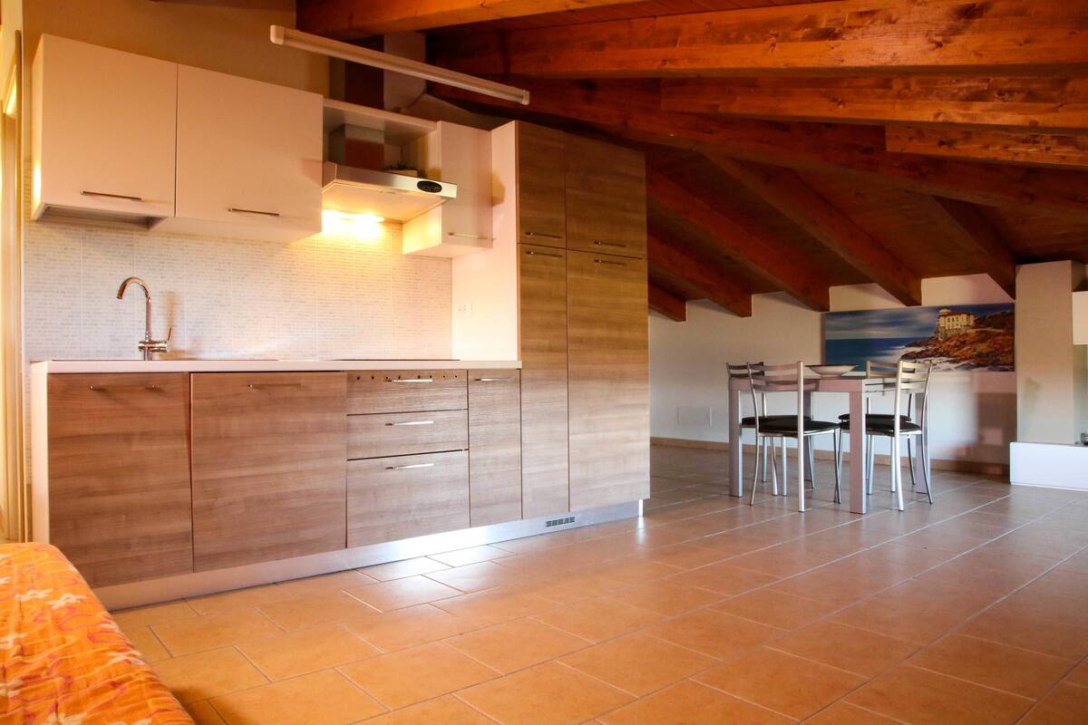 A modern kitchen with wooden cabinets, a built-in stove, and a dining area with chairs.
