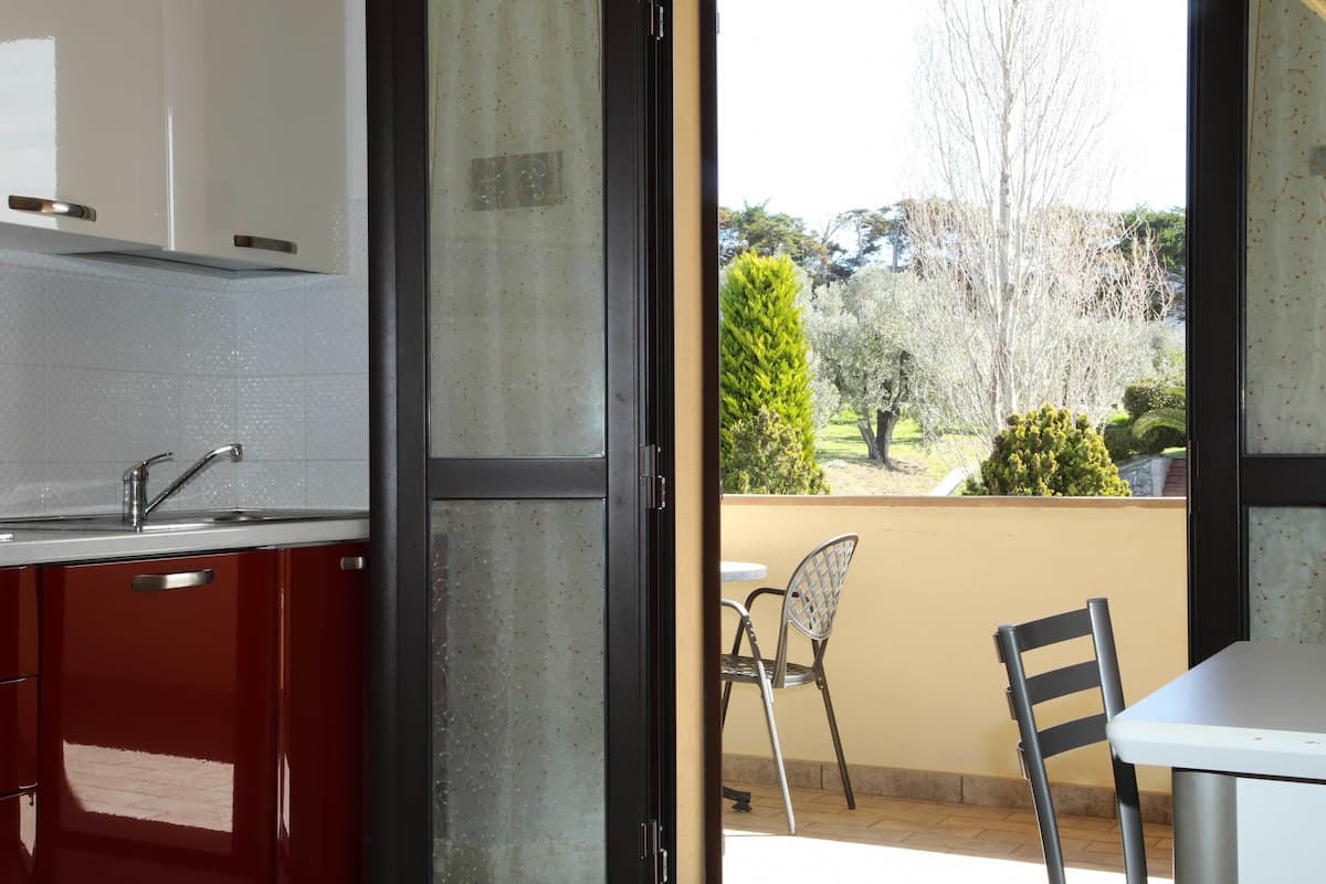 A kitchen with a sink, cabinets, and a view of a balcony with a table and chairs.