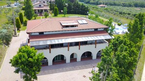 A two-story building with a tiled roof, arched windows, and a courtyard with outdoor seating. - Agriturismo San Gregorio (San Vincenzo)