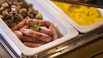 A buffet with various food items including sausages, mushrooms, and a yellow dish.
